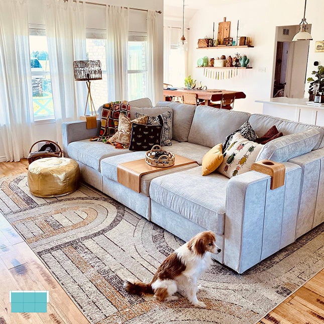 Living room with a large sactional couch set-up and a dog on the side.