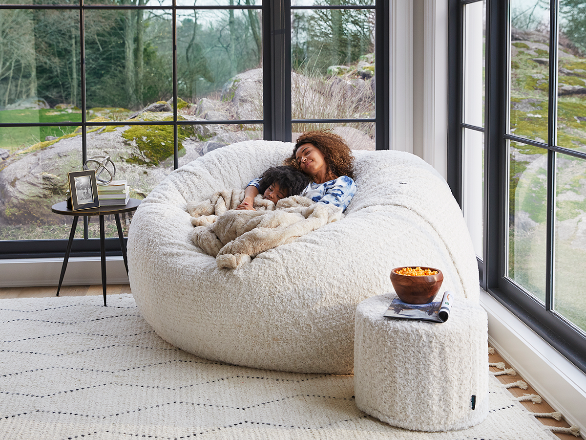 Woman cuddled up with her child using a Lovesac Footsac.