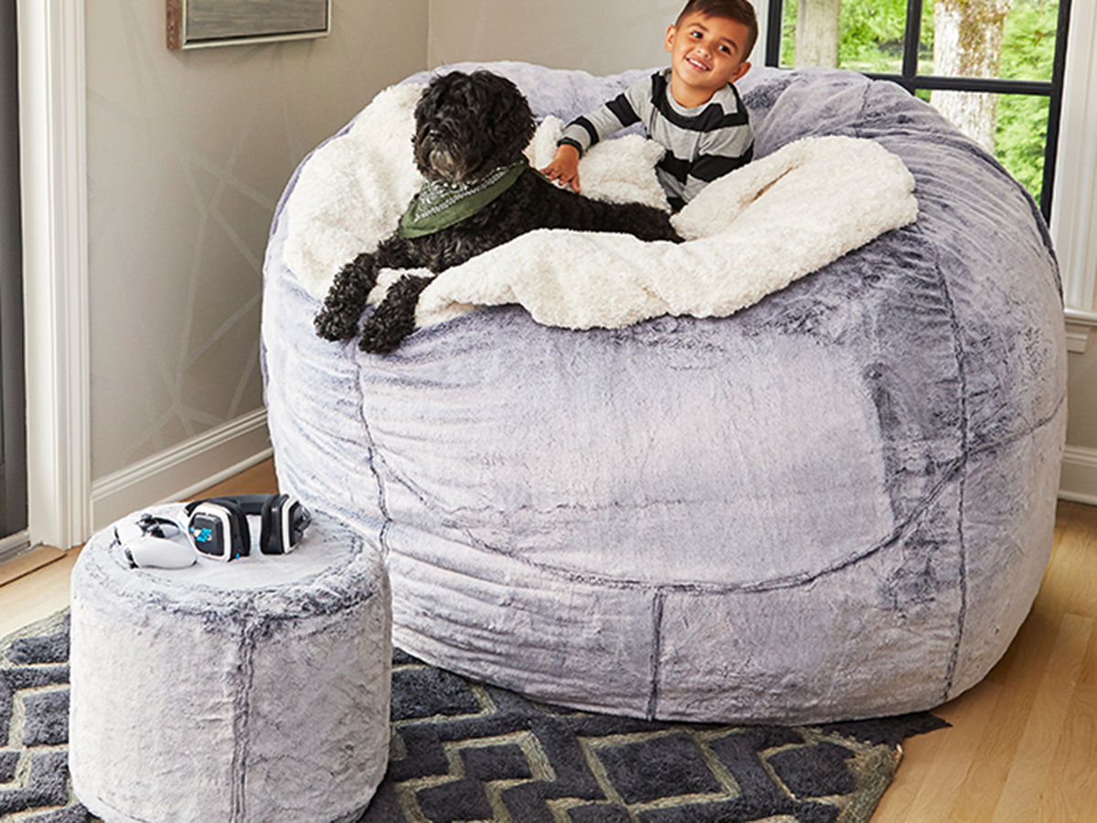 Boy smiling and relaxing with his dog while on a Lovesac beanbag.